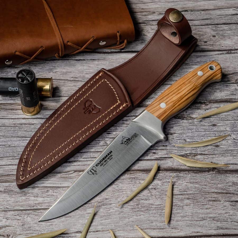 Cudeman Rhyno Hunter jagtkniv 15 cm med oliventræskaft og læderskede på træbord